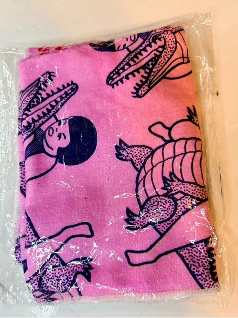 Funny pink dish / tea towel with a repeating print of a person wrestling an alli
